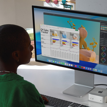 Người phụ nữ ngồi ở bàn làm việc và thao tác trong bảng tính Excel trên máy Mac. Bảng tính Excel là bảng theo dõi doanh số bán hàng Quý 4. Phía sau cửa sổ bảng tính Excel là cửa sổ Pixelmator Pro.